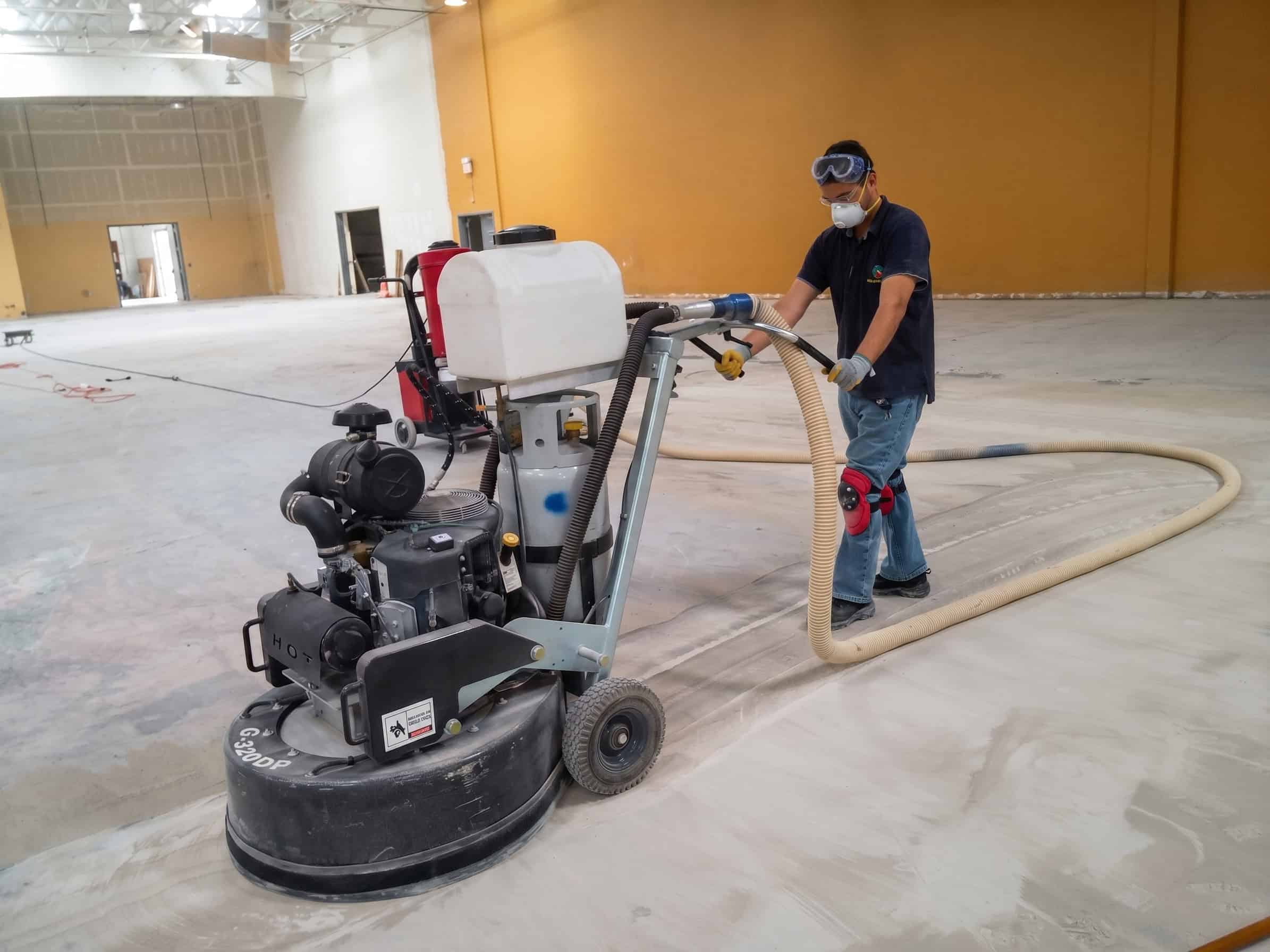 An IT'S SO CLEAN technician running a planetary grinder with dust extraction on an interior floor
