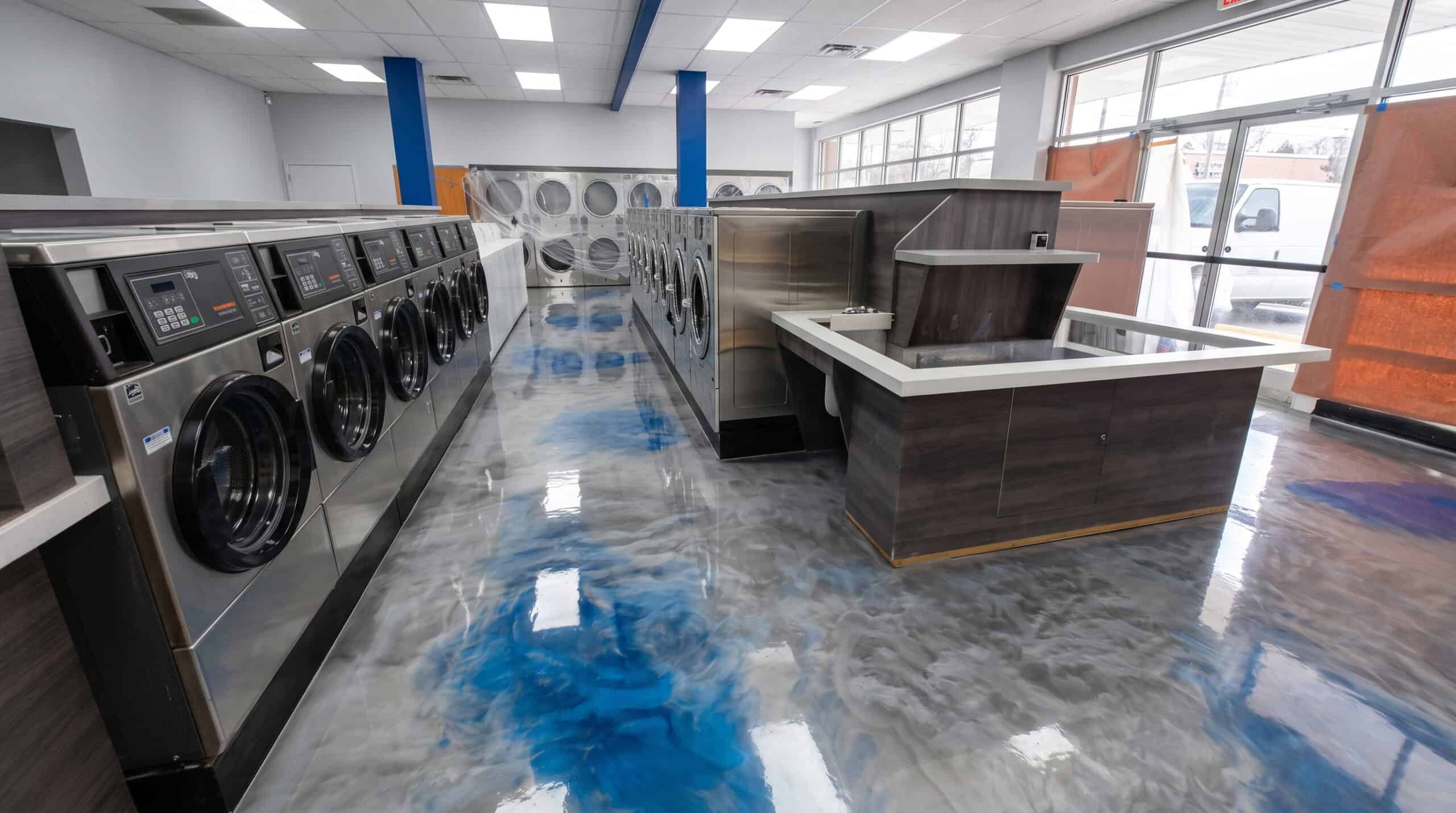 Blue and white metallic epoxy floor running through a commercial laundromat
