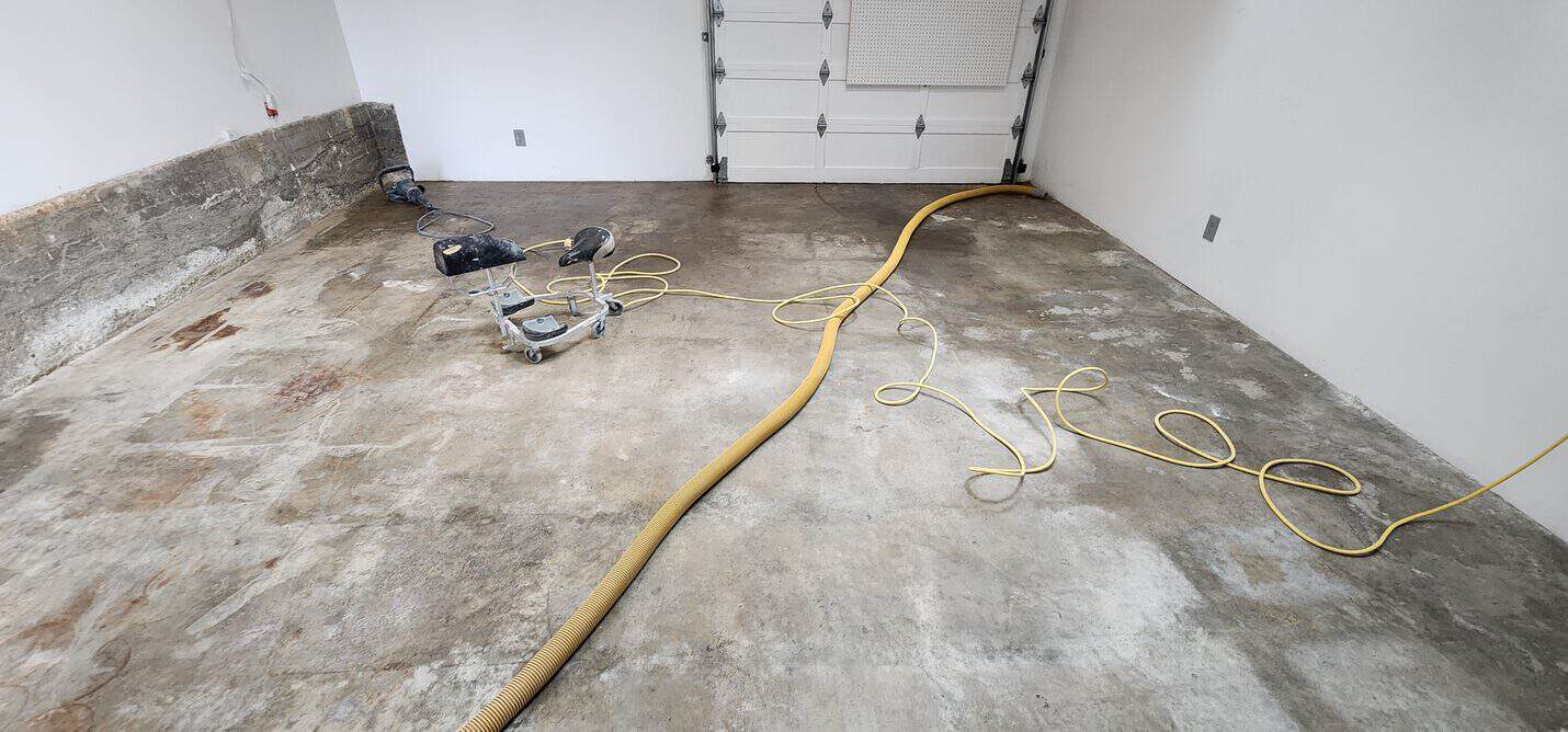 Bare slab prepared for clear epoxy, garage door still in place