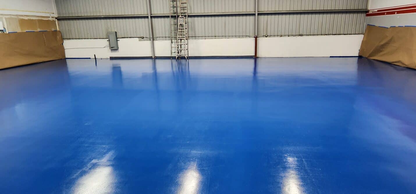 Blue metallic hangar floor reflecting the roof lights