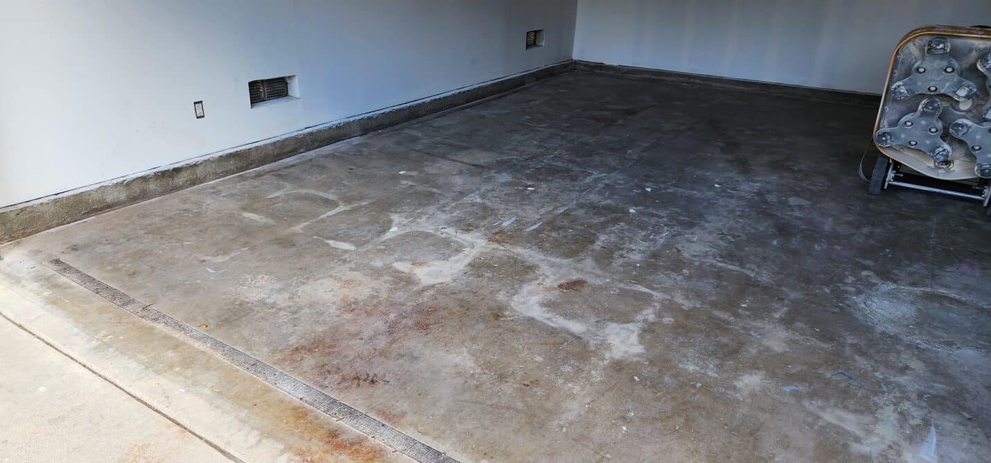 Stained garage floor showing tyre marks and old concrete patches