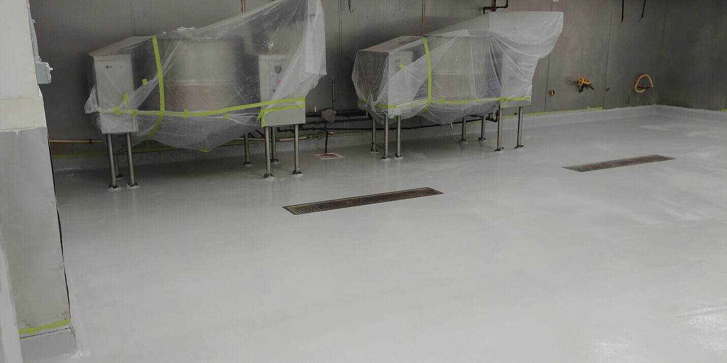 Grey epoxy kitchen floor laid to the trench drains